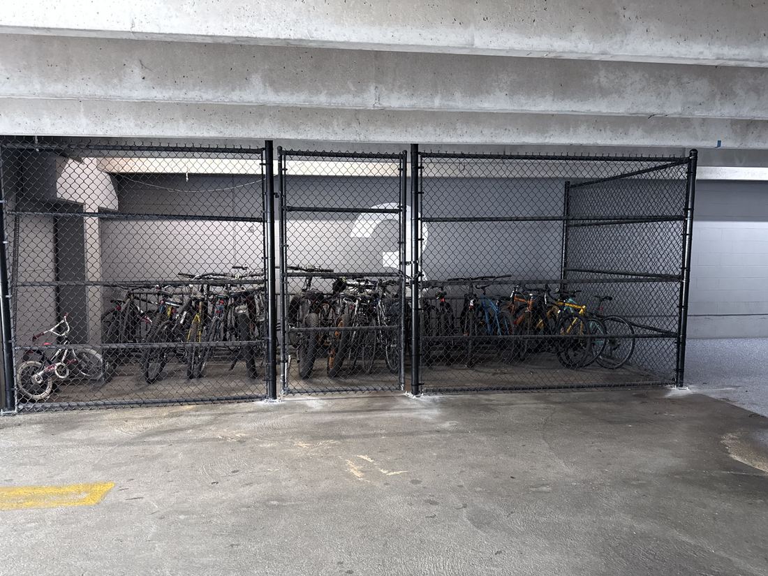 Eight-foot black chain-link enclosure protecting secured bike storage in a parking deck, installed by FenceWorks of Georgia