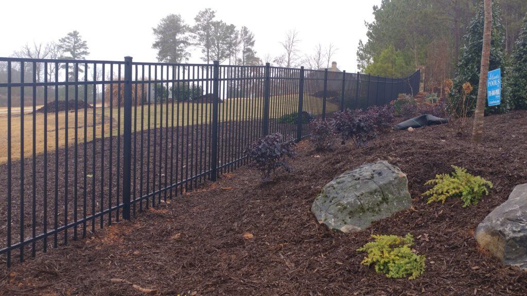 Black smooth-top aluminum fence beside a brick home
