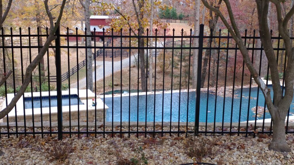 Black pressed-point spear-top aluminum fence running along a wooded property line, installed by FenceWorks of Georgia