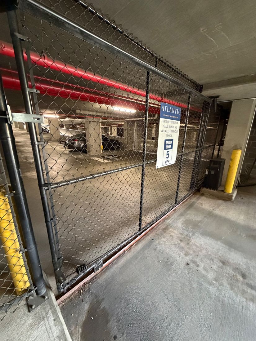 Automated black chain link slide gate at a parking garage