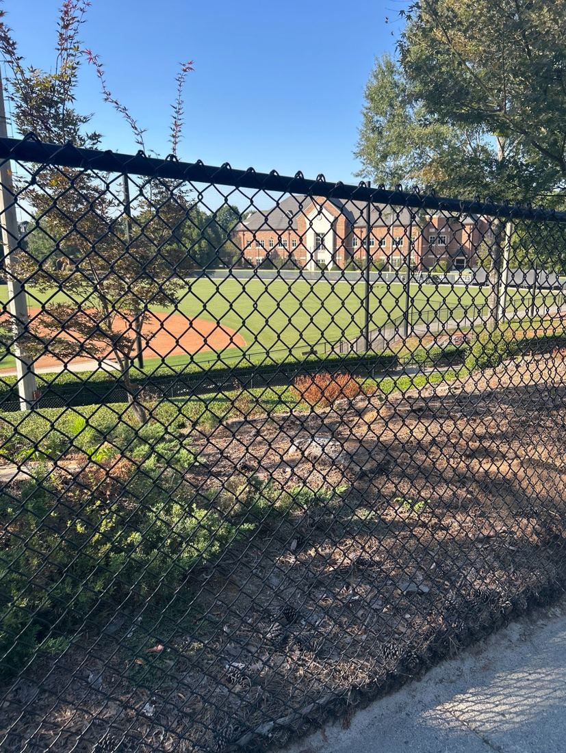 Black chain-link fence along a school baseball field