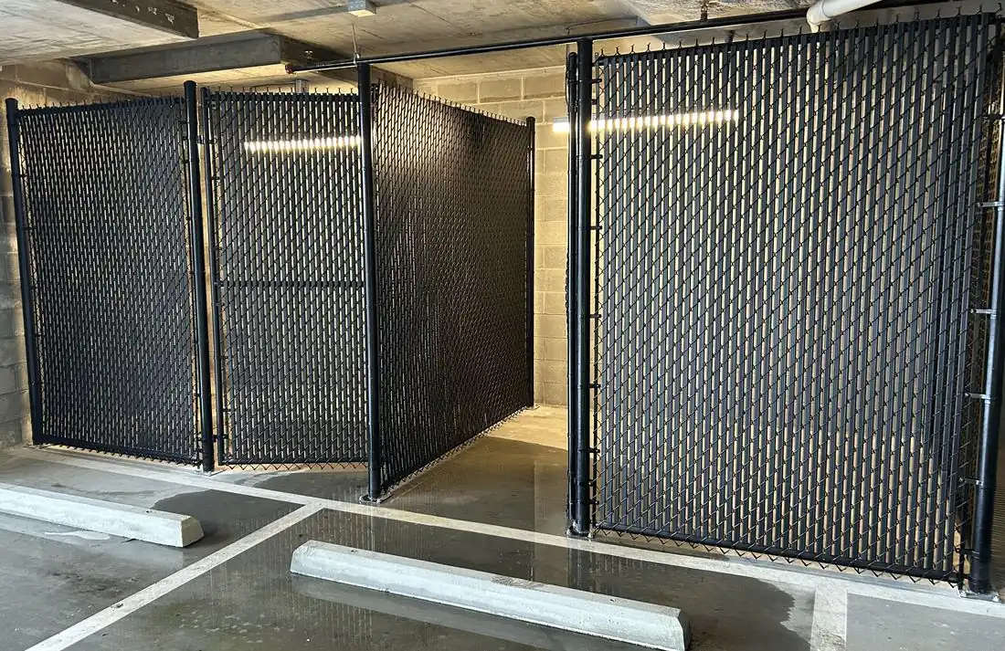Black chain-link storage cages with privacy slats installed in a parking deck by FenceWorks of Georgia