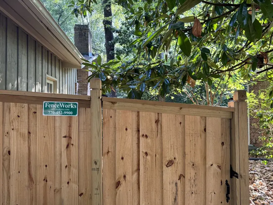 Board-on-board capped wood privacy fence with dado posts along a residential back yard, built by FenceWorks of Georgia