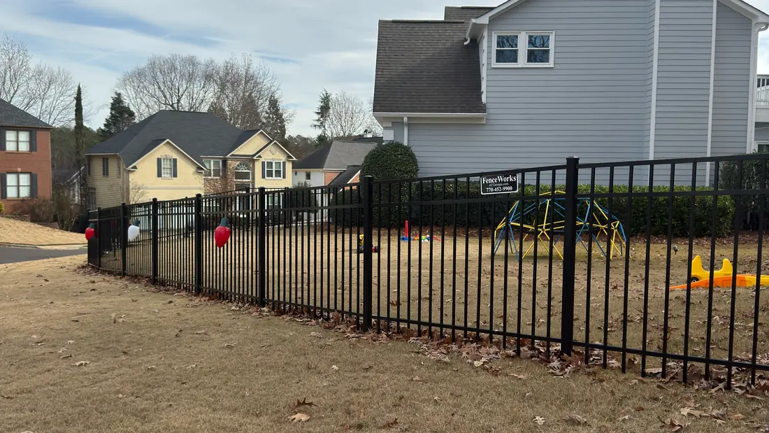 Black flat-top aluminum fence with a FenceWorks of Georgia job sign enclosing a Peachtree Corners back yard