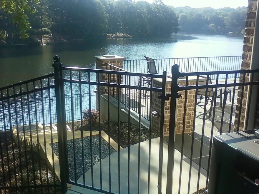 Black powder-coated ornamental steel flat-top fence between stone columns at a metro Atlanta property