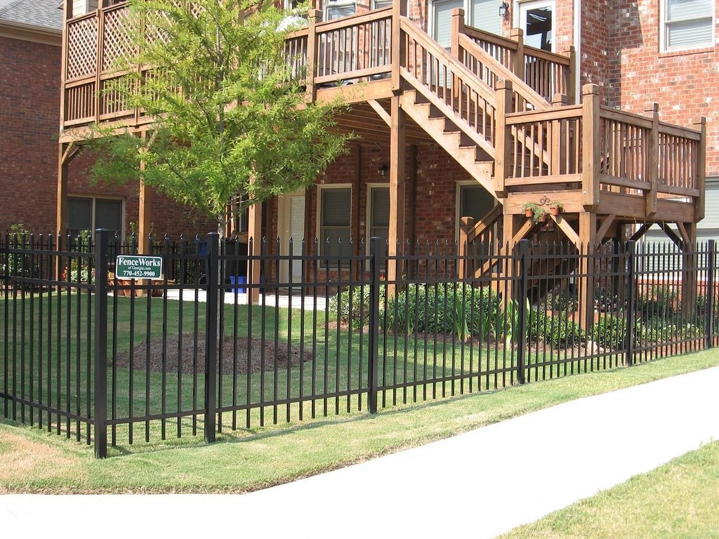 Black spear-top ornamental metal fence along a brick home — the classic wrought-iron look