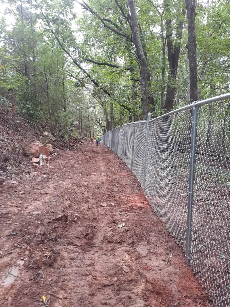 Galvanized chain link fence following a wooded slope in Kennesaw, GA, installed by FenceWorks of Georgia