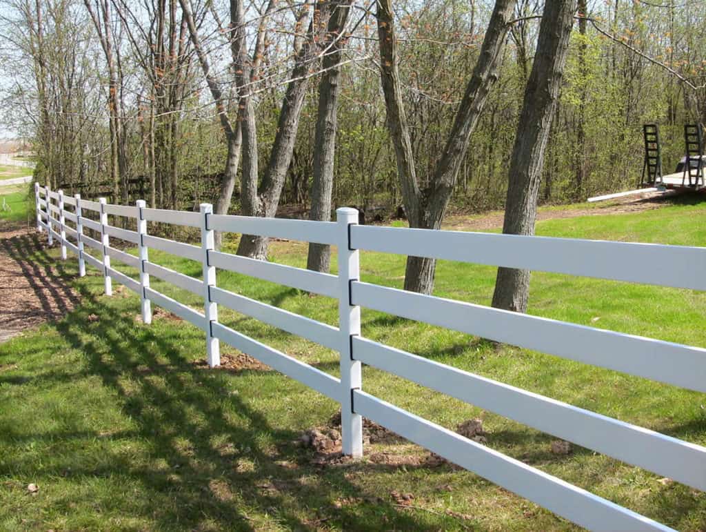 White four-rail Buckley steel board fence running along the edge of a wooded lawn, installed by FenceWorks of Georgia