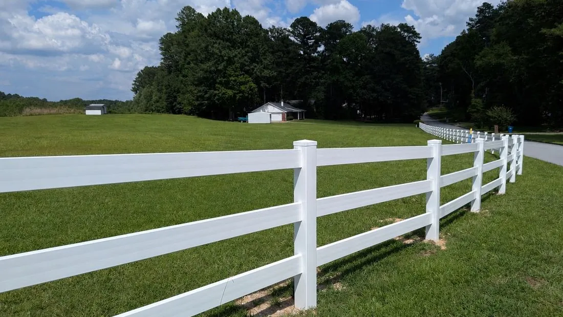 White vinyl 3-rail ranch rail fence along a pasture, installed by FenceWorks of Georgia