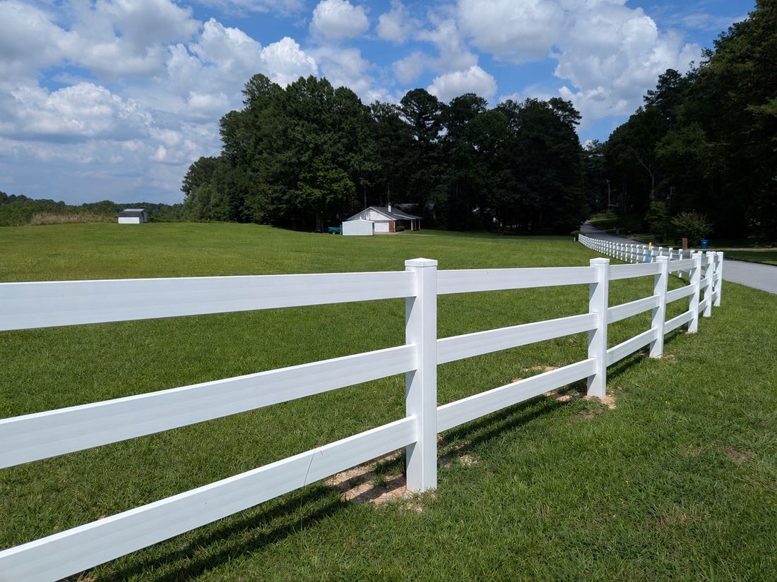 White vinyl three-rail ranch rail fence along a pasture, installed by FenceWorks in metro Atlanta
