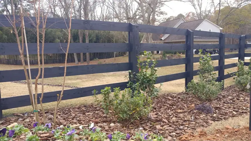 Black four-rail wood ranch rail fence installed by FenceWorks on a metro-Atlanta property