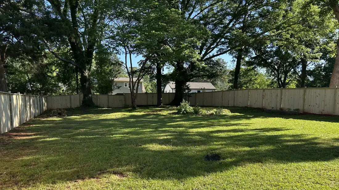 Capped wood privacy fence with flat posts enclosing a large shaded back yard, built by FenceWorks of Georgia