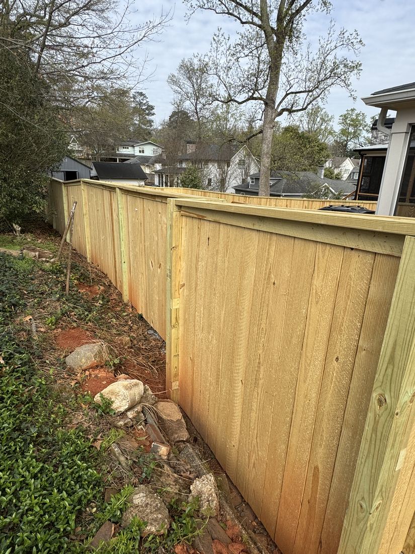 Capped wood privacy fence with a flat top and exposed posts
