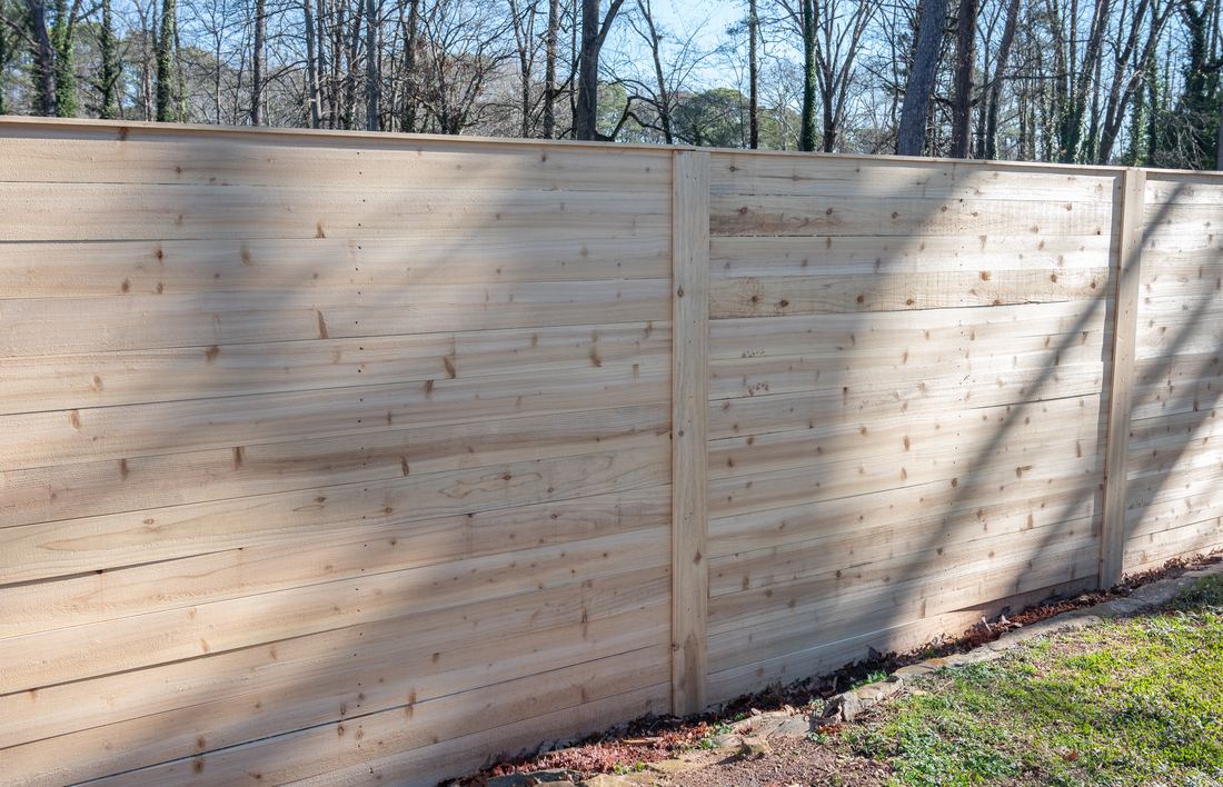 Horizontal capped wood privacy fence along a residential backyard, built by FenceWorks of Georgia