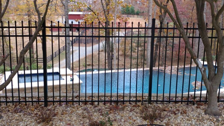 Spear-top black aluminum fence with press-point pickets beside a backyard pool